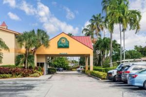 劳德代尔堡La Quinta by Wyndham Fort Lauderdale Pompano Beach的停车场内有车辆的旅馆