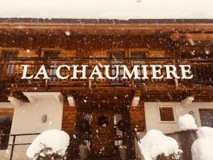 莱热Résidence La Chaumière的雪中建筑物的侧面标志