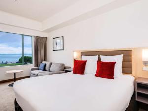 罗托鲁瓦罗托鲁阿湖畔诺富特酒店的酒店客房配有一张带红色枕头的大床