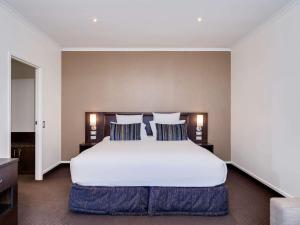 罗托鲁瓦罗托鲁阿湖畔诺富特酒店的卧室配有带蓝色枕头的大型白色床
