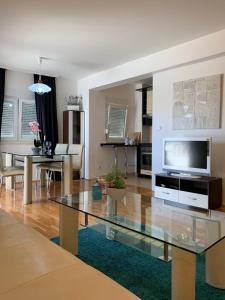 特罗吉尔Apartments Villa Plaza的客厅配有玻璃桌和电视
