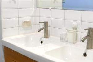 恒春古城仁旅宿的浴室水槽设有2个水龙头和镜子