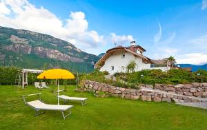 奥拉Villa Trogerhof的黄色遮阳伞和两把椅子,房子
