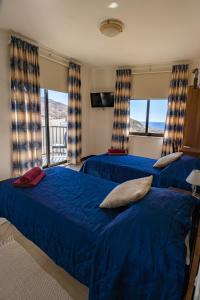 马萨尔福恩落日海景公寓式酒店的卧室设有两张床铺、蓝色床单和窗户。