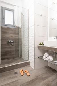 萨尔蒂Almare Seaside Studios & Suites - Sarti Sithonia的带淋浴的浴室和地板上的两双鞋