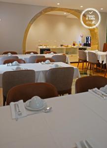 托马尔Casa dos Ofícios Hotel的一间设有白色桌椅的用餐室
