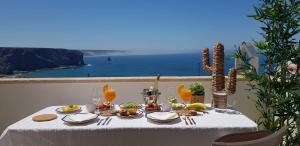 阿尔热祖尔Apartment Praia Arrifana with BALCONY and SEA VIEW的一张桌子,上面摆放着食品和饮料,并享有海景