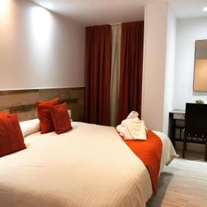 埃尔蓬特Hotel tres estrellas Casa Maribona Gela的一间卧室配有两张带红色窗帘的床和一张书桌