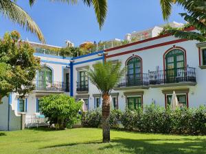 莫甘海滩Billy's Puerto de Mogán Apartments by LIVVO的前面有棕榈树的建筑
