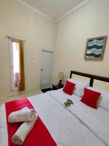 茂物Bakom Inn Syariah的卧室配有带红色枕头的大型白色床