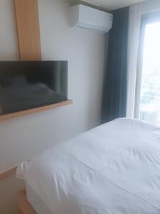 束草市Sokcho Daemyung Heidi Pension的卧室配有白色的床和墙上的电视。
