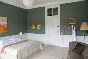 FaxeVemmetofte Præstegård的一间卧室设有绿色的墙壁、一张床和椅子