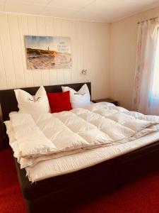 NeuhausFerienwohnung Thiemig的一张配有白色床单和红色枕头的大床