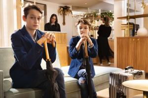 巴黎Hôtel Gramont的两个男孩坐在沙发上,把伞放在