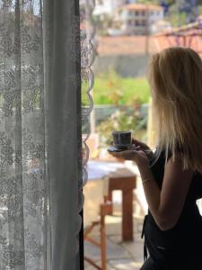 寇特Athina Studios的一边拿着咖啡一边望着窗外的女人