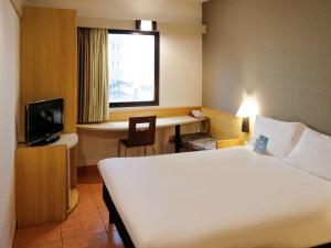桑托斯ibis Santos Gonzaga Praia的酒店客房配有一张床、一张书桌和一台电视。