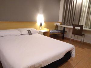 桑托斯ibis Santos Gonzaga Praia的酒店客房设有一张白色大床和椅子