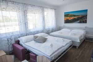 米库洛夫Apartmány Pemag Mikulov的配有2张床的白色墙壁和窗户客房
