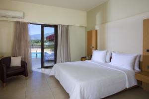 卡拉马塔伊利特城市度假酒店的卧室配有一张白色大床和一把椅子