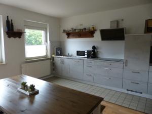 OberhausenDie Gefährten的厨房配有白色橱柜和木桌