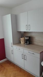 盖布利茨Ferienwohnung Madlene 1的厨房配有白色橱柜和台面上的咖啡机。