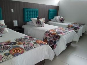 马尼萨莱斯Hotel Grato Manizales的酒店客房内的三张床,配有色彩缤纷的毯子