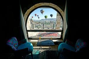 格雷梅Arinna Cappadocia的一间设有两把椅子和一个带热气球的窗户的房间