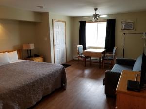 奥索尤斯Osoyoos Lakeview Inn & Suites的酒店客房带一张床、一张桌子和椅子