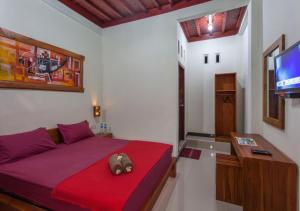 龙目岛库塔Kintari Indah Homestay的一间卧室配有红色的床和电视