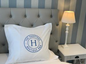 根特The Hamptons Boutique B&B的床上的枕头,桌子上有一盏灯