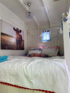 东福尔讷Little blue house (on the campsite)的卧室配有一张床,墙上挂着一头牛的照片