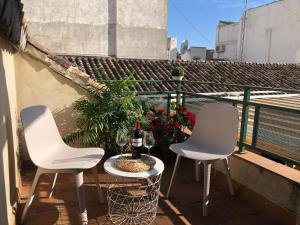 格拉纳达ISA Granada的阳台上配有两把白色椅子和一瓶葡萄酒