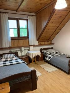 新古提Agroturystyka u Królów的客房设有两张床铺、木制天花板和窗户。