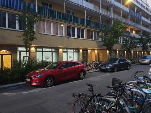 维也纳Gabriel´s Apartments的一辆红色的汽车停在一座建筑物前面,上面有自行车