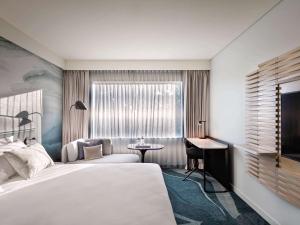 汉密尔顿诺富特泰努伊汉密尔顿酒店的一间卧室配有一张床、一张书桌和一个窗户。