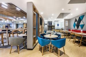 沃特福德快捷假日伦敦-沃特福德岔口酒店的一间设有蓝色桌椅的餐厅和一间酒吧