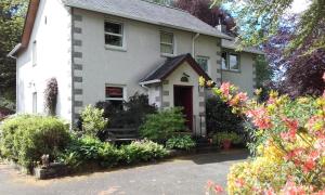 柯克宾Grovewood House Retreat的白色的房子,有红色的门和一些花