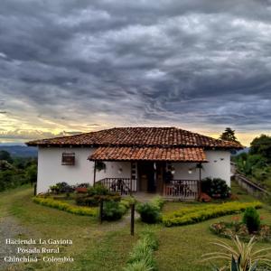 ChinchináHacienda Cafetera La Gaviota的白色的小房子,带有茅草屋顶