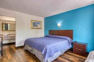 橘园Zen Living Suites Extended Stay - Jacksonville - Orange Park的一间卧室配有一张蓝色墙壁的床