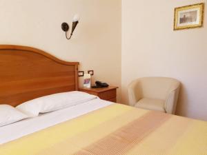 吉泽里亚勒阿文尼尔餐厅酒店的一间卧室配有一张床、一把椅子和一盏灯