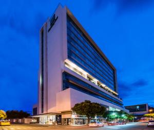库库塔Holiday Inn Cúcuta, an IHG Hotel的一座高大的白色建筑,前面有汽车停放
