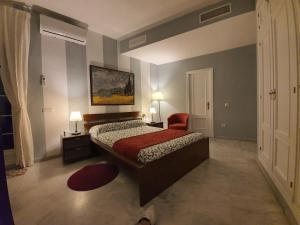 塞维利亚阿提科圣克莱门特公寓的一间卧室配有一张床和一张红色椅子