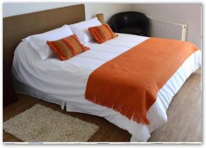 蓬塔阿雷纳斯奇岚格公寓式酒店的一张配有橙色和白色床单及枕头的大床