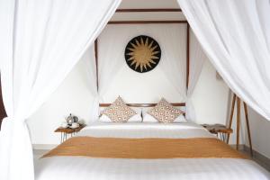 姆杜克阿约塔玛花园别墅的一间卧室配有一张带白色窗帘和时钟的床