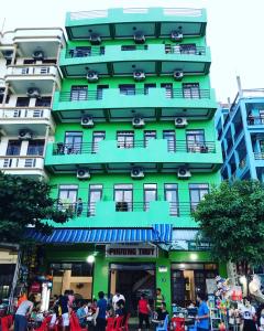 岑山Phương Thuỷ Hotel的一座绿色建筑,前面的人在步行