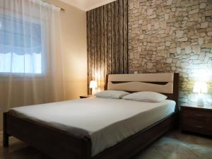 尼亚普拉莫斯Iro Apartment的一间卧室设有一张大床和石墙