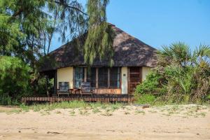 SaadaniSaadani Safari Lodge的海滩上带茅草屋顶的房子