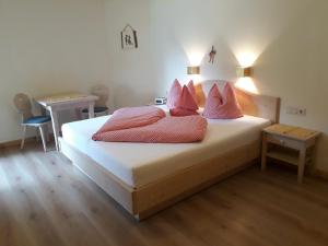 坦海姆Biobauernhof Vilshof的一间卧室配有一张带粉色枕头的床和一张书桌