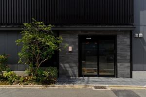 京都ikoi HOTEL的黑色的建筑,有门和树