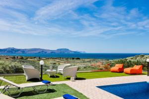 埃皮斯科皮·罗希姆诺Nereid Villa, summer feeling, By ThinkVilla的一个带白色椅子的庭院和一个游泳池